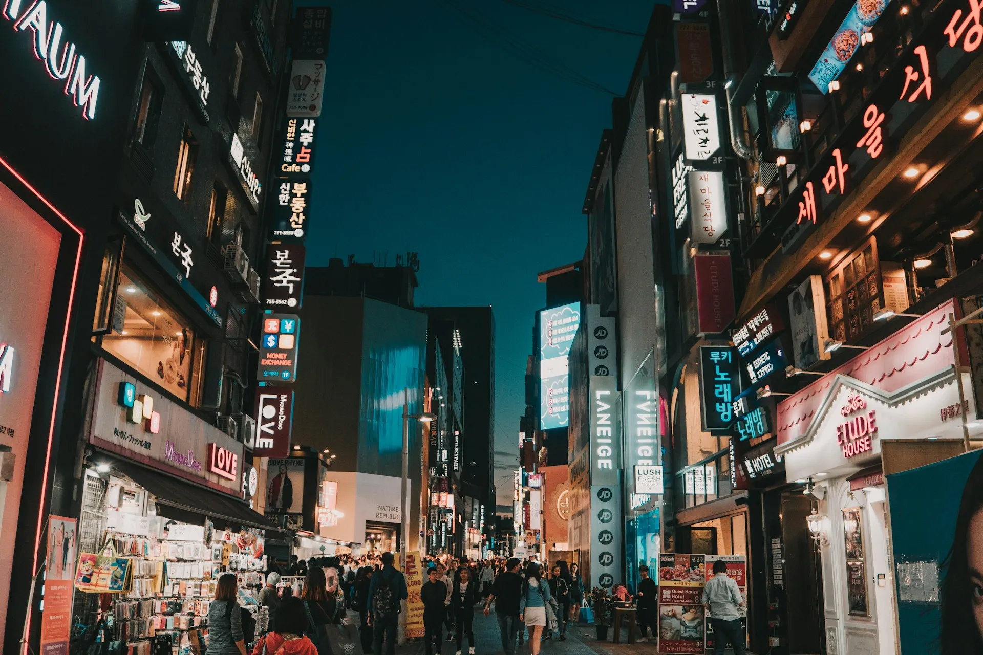 Bustling Myeongdong shopping street at night with neon lights